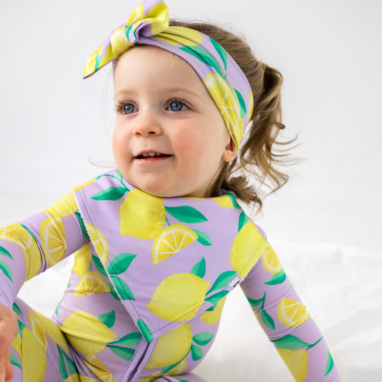 Sitting child wearing the Lavender Sunny Citrus Bandana Bib