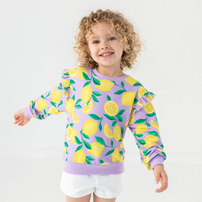 Standing child wearing the Lavender Sunny Citrus Flutter Crewneck