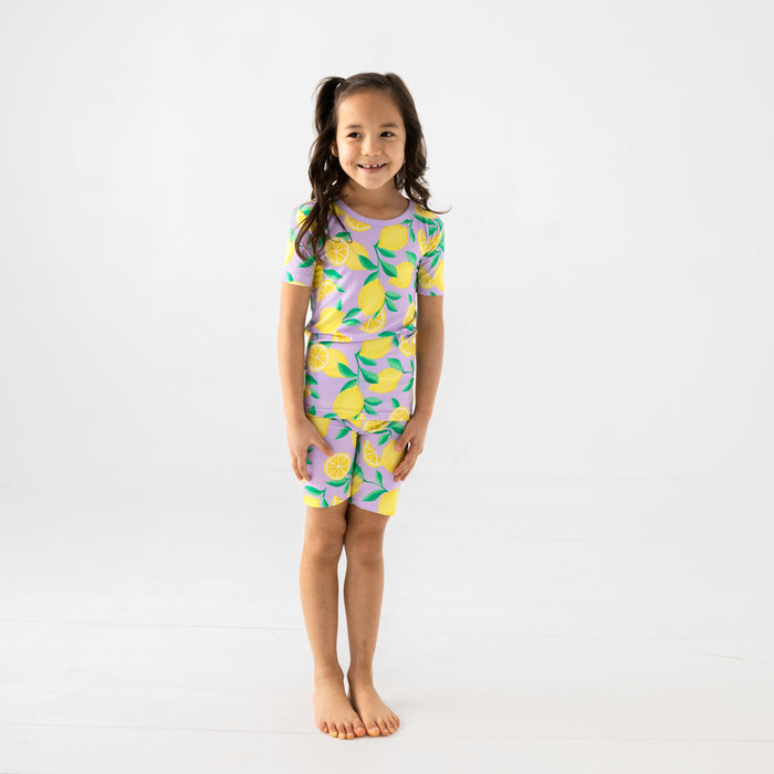 Standing child wearing the Lavender Sunny Citrus Two-Piece Short Sleeve & Shorts Pajama Set