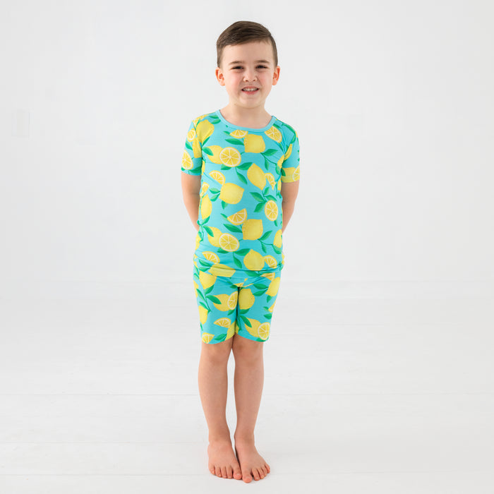 Standing child wearing the Blue Sunny Citrus Two-Piece Short Sleeve & Shorts Pajama Set