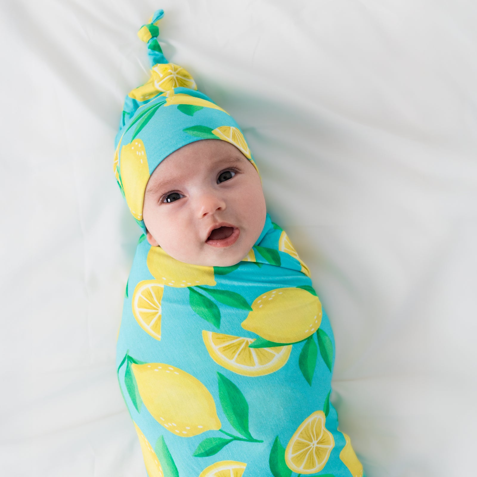 Close up of child wearing the Blue Sunny Citrus Swaddle & Hat Set