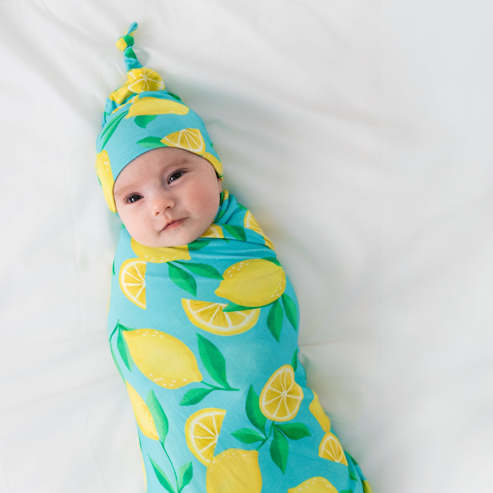 Aerial view of child wearing the Blue Sunny Citrus Swaddle & Hat Set