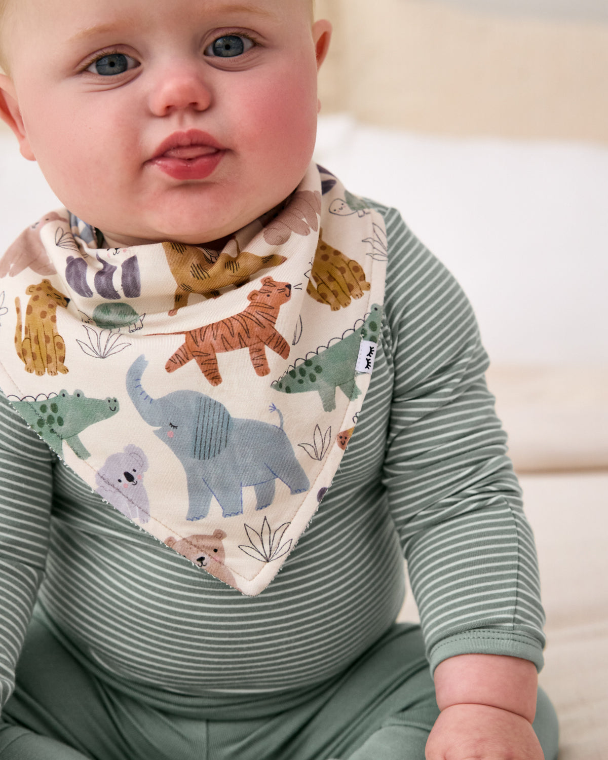 Close up of baby wearing the Sweet Safari Bandana Bib with a green striped baby bodysuit