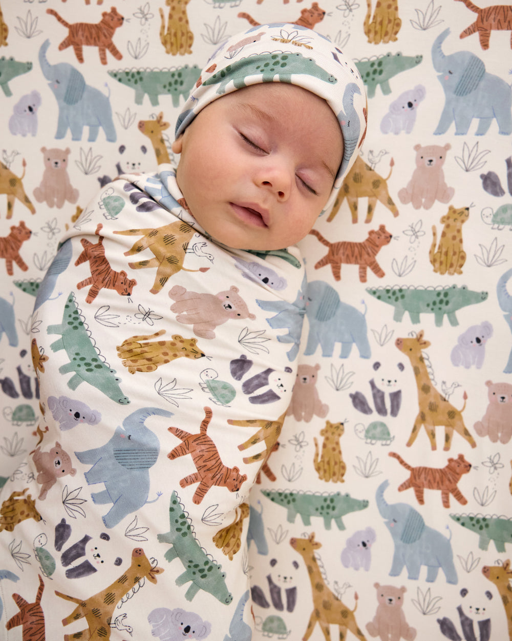 Aerial view of baby swaddled in the Sweet Safari Swaddle & Infant Beanie Set