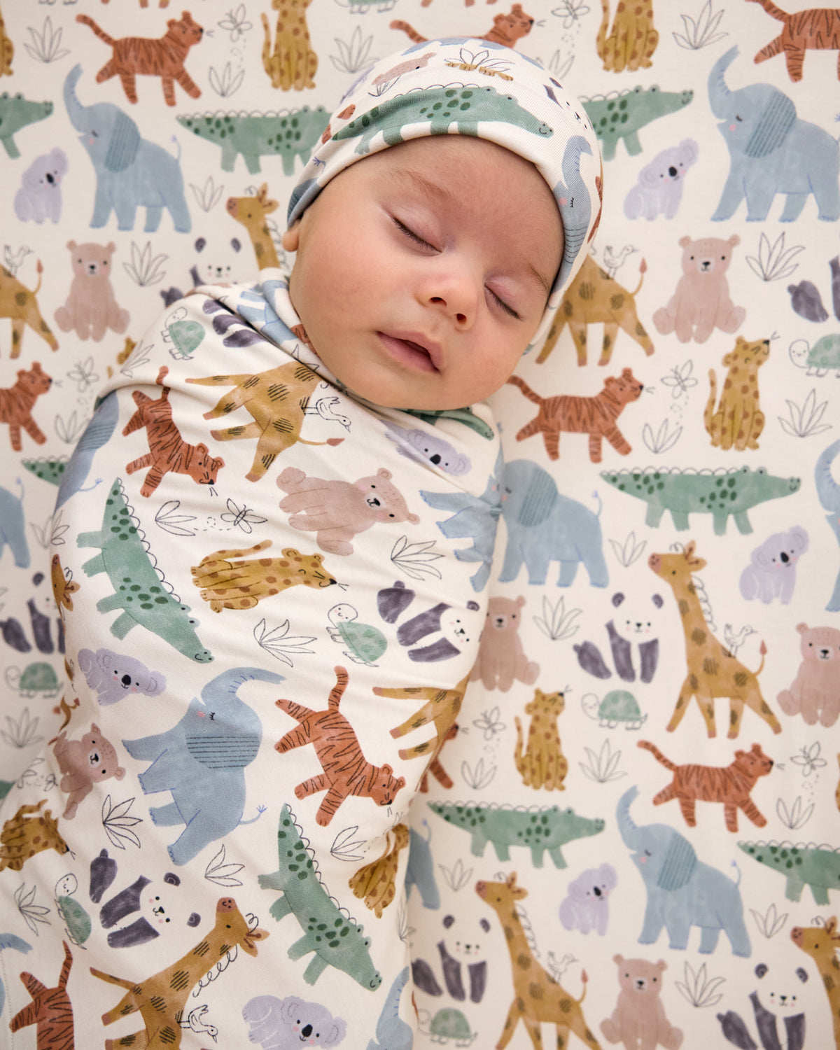 Aerial view of baby swaddled in the Sweet Safari Swaddle & Infant Beanie Set