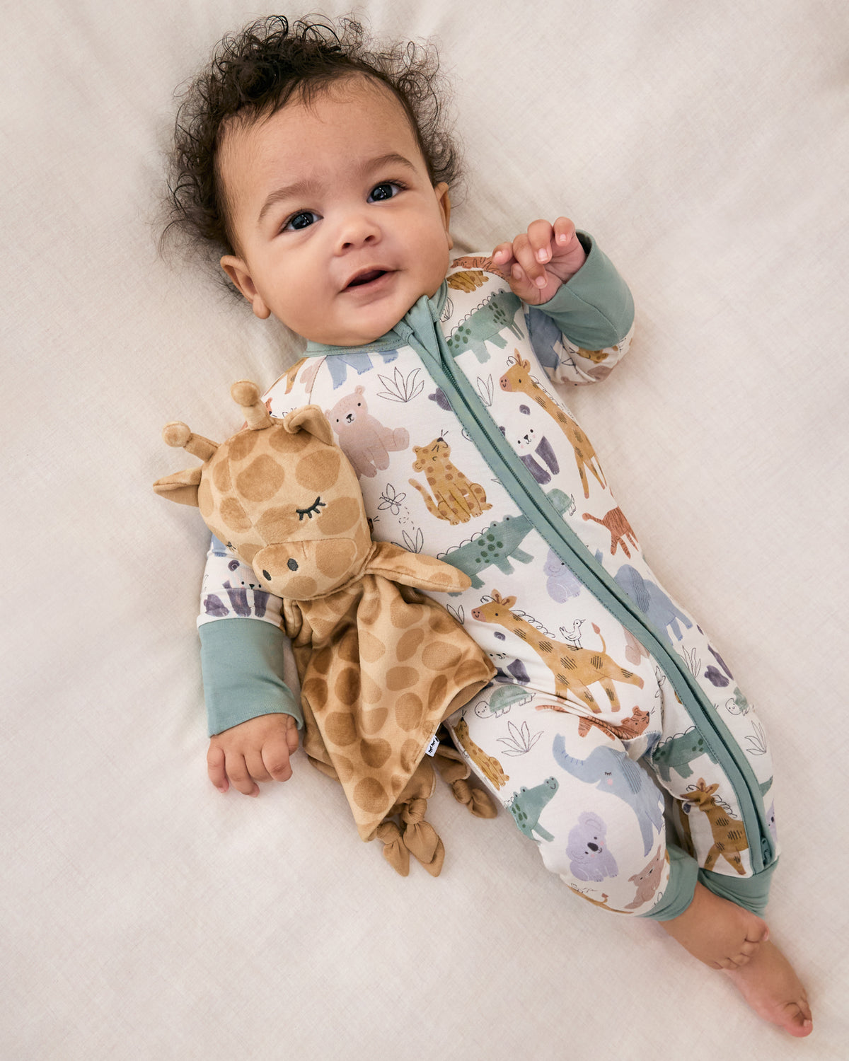 Aerial view of newborn wearing the Sweet Safari Zippy cuddling with a giraffe lovey