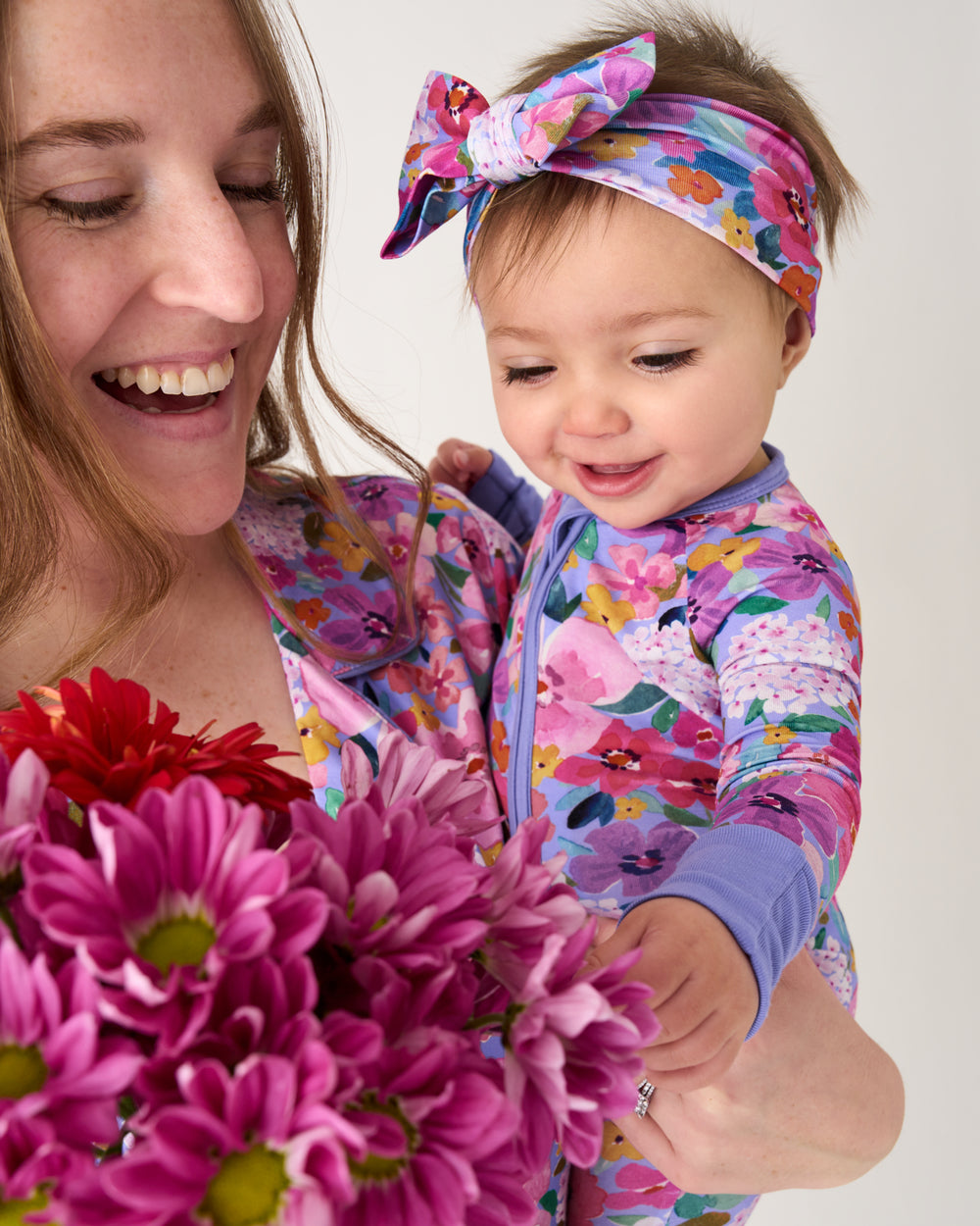 Mother holding daughter wearing the Sweet Sprigs Luxe Bow Headband and Zipper Pajamas