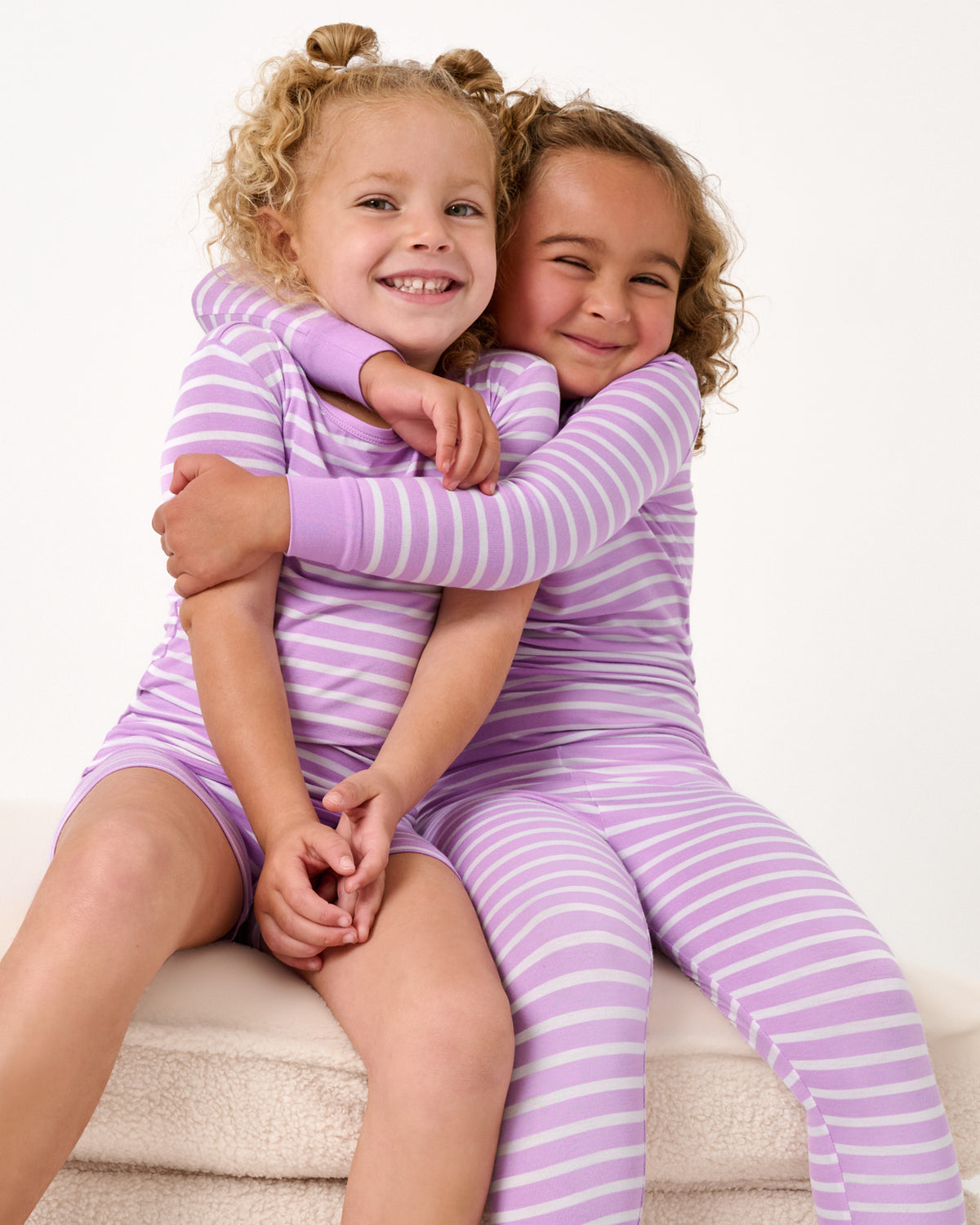 Close up of two girls wearing matching Sweet Orchid Stripe Two-Piece Pajama Sets