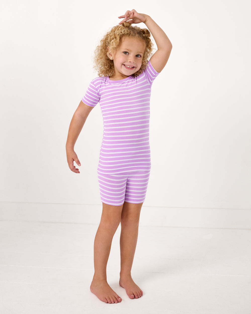 Standing girl wearing the Sweet Orchid Stripe Two-Piece Short Sleeve & Shorts Pajama Set