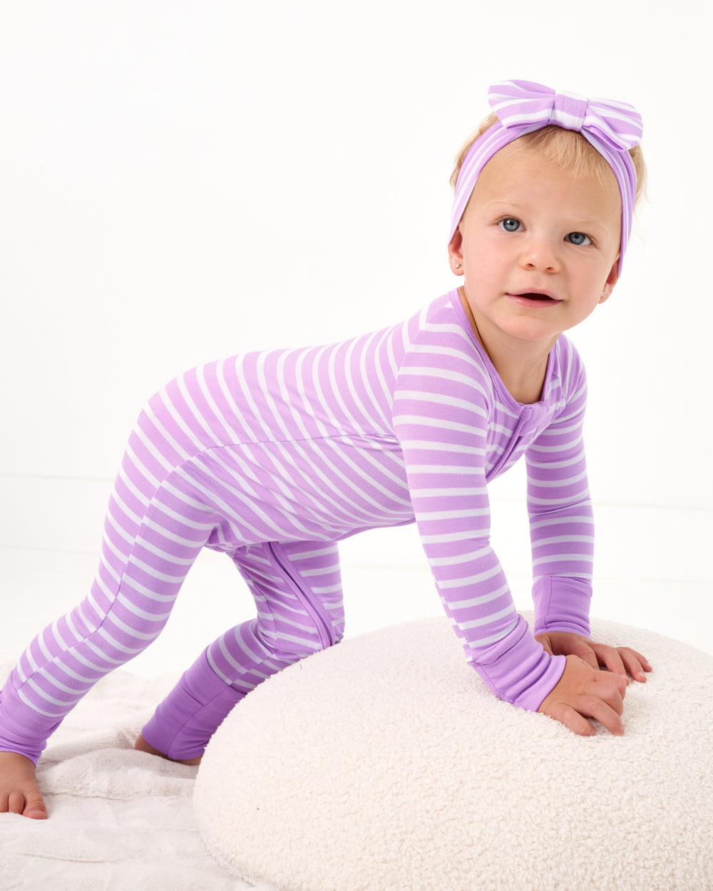 Child crawling on a boucle pouf wearing the Sweet Orchid Stripe Zippy