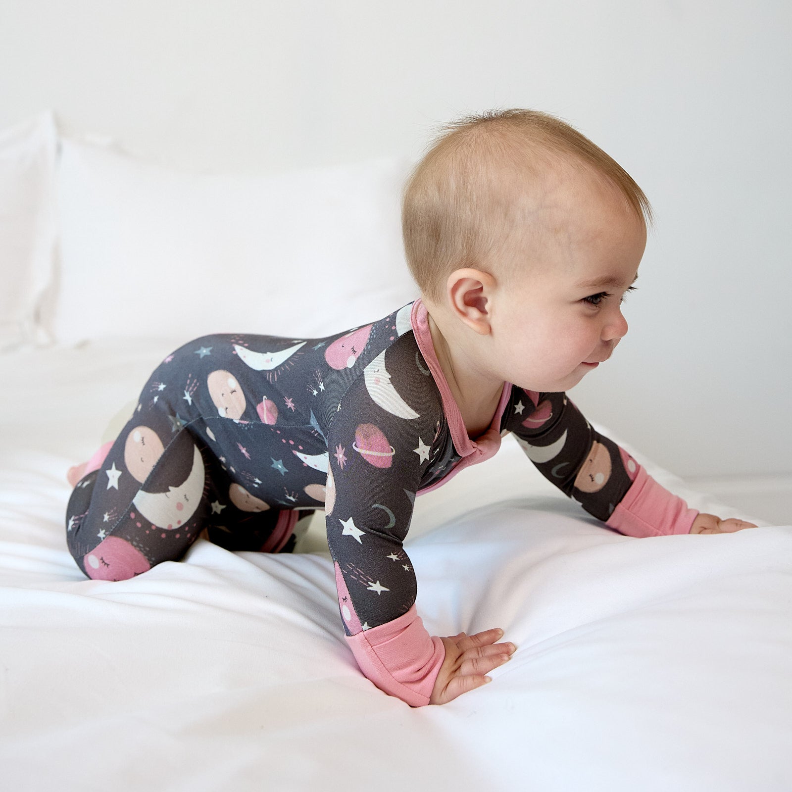 baby wearing pink to the moon & back zippy crawling on bed