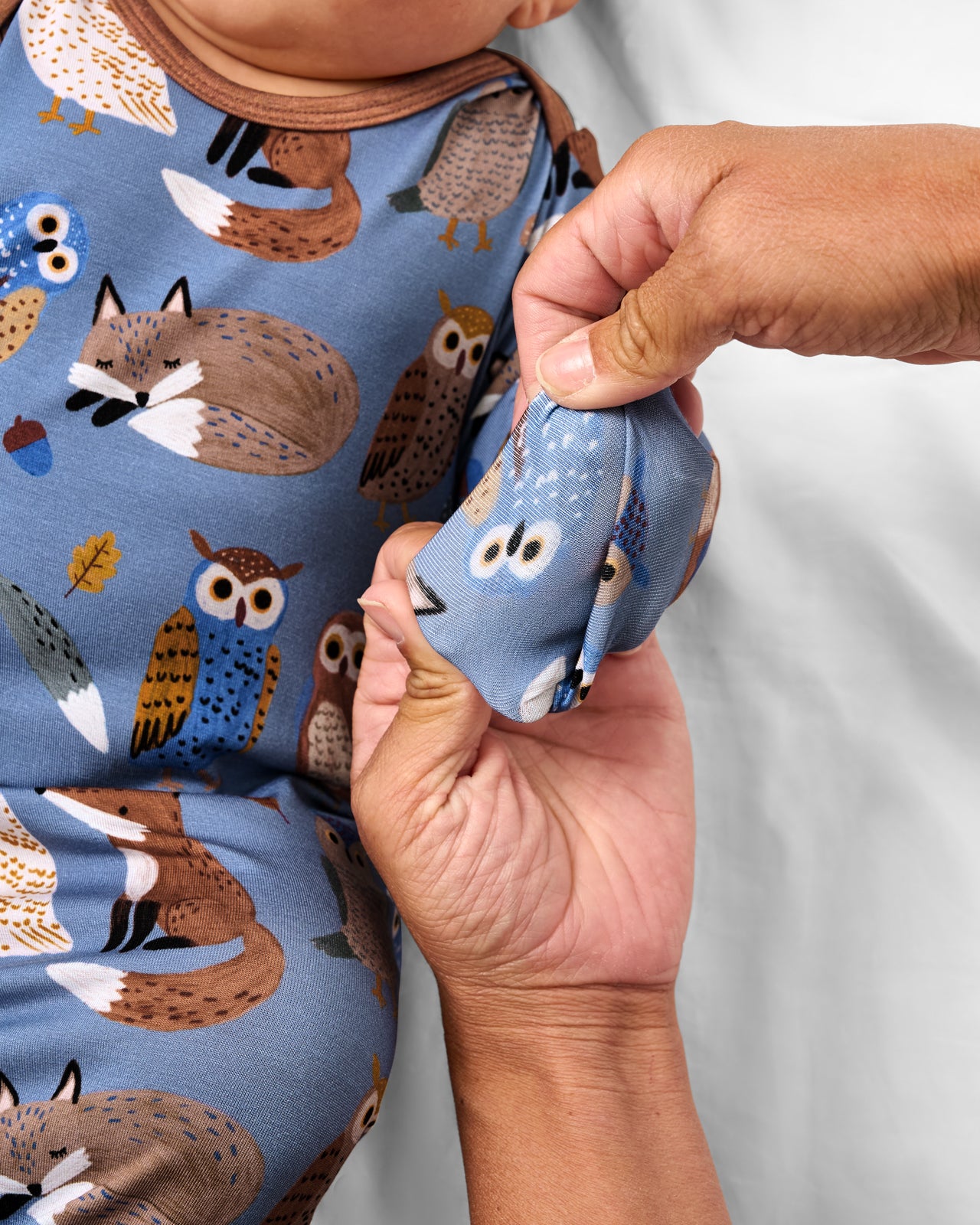 Adult demonstrating the mitten feature on the Twilight Pals Infant Gown