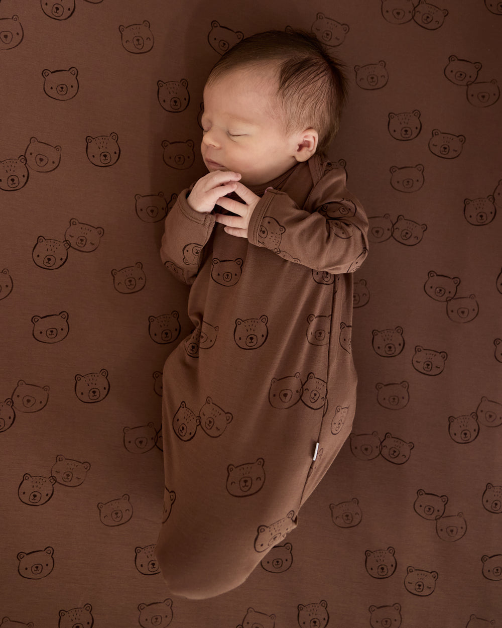 Baby wearing the Teddy Tracks Infant Gown on a matching crib sheet