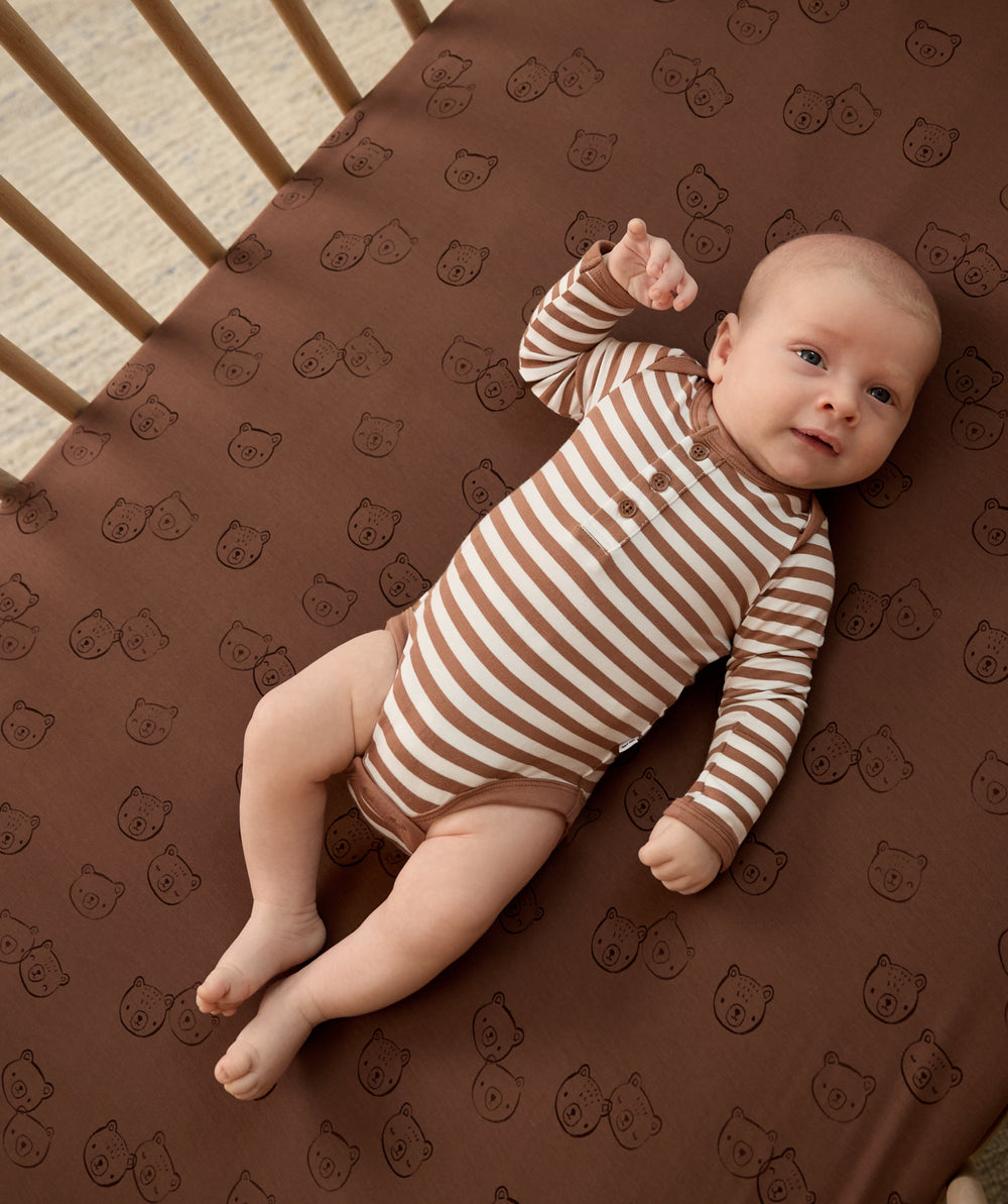 Newborn laying on the Teddy Tracks Fitted Crib Sheet