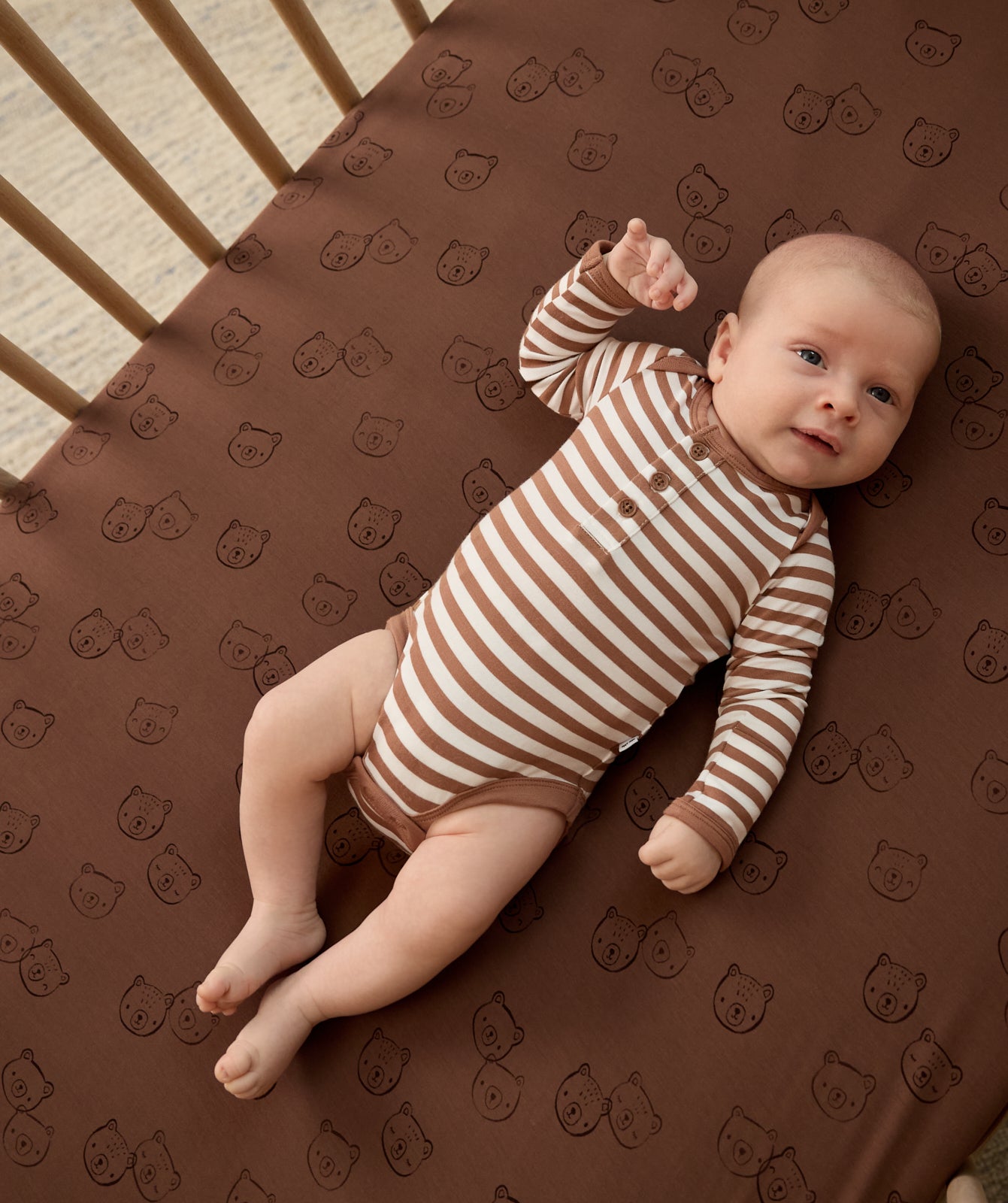 Newborn laying on the Teddy Tracks Fitted Crib Sheet