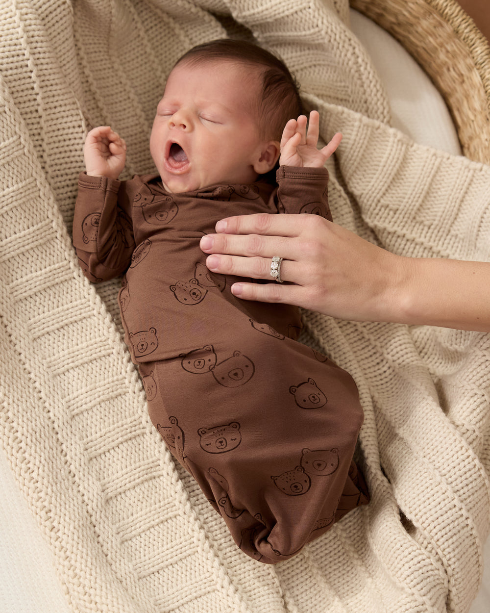 Newborn wearing the Teddy Tracks Infant Gown on a knit blanket