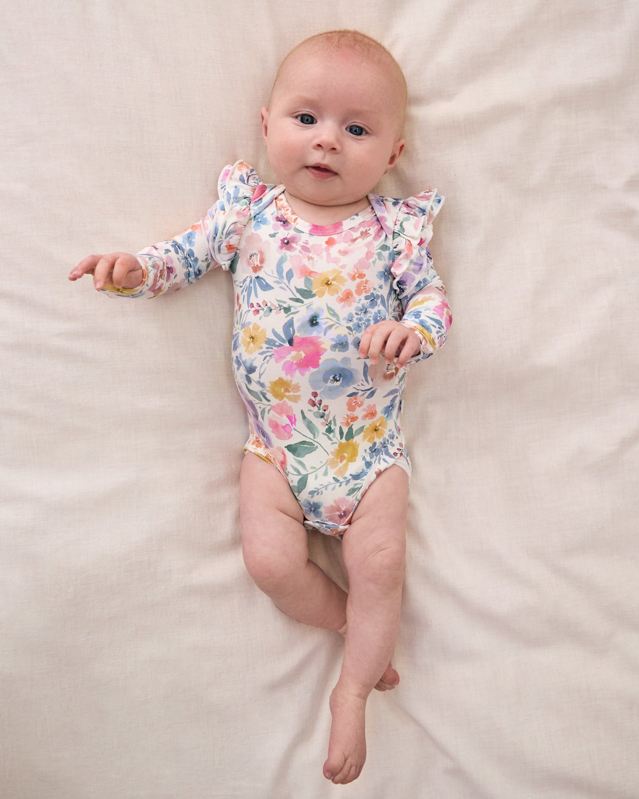 Aerial view of newborn wearing the Tiny Blooms Flutter Bodysuit