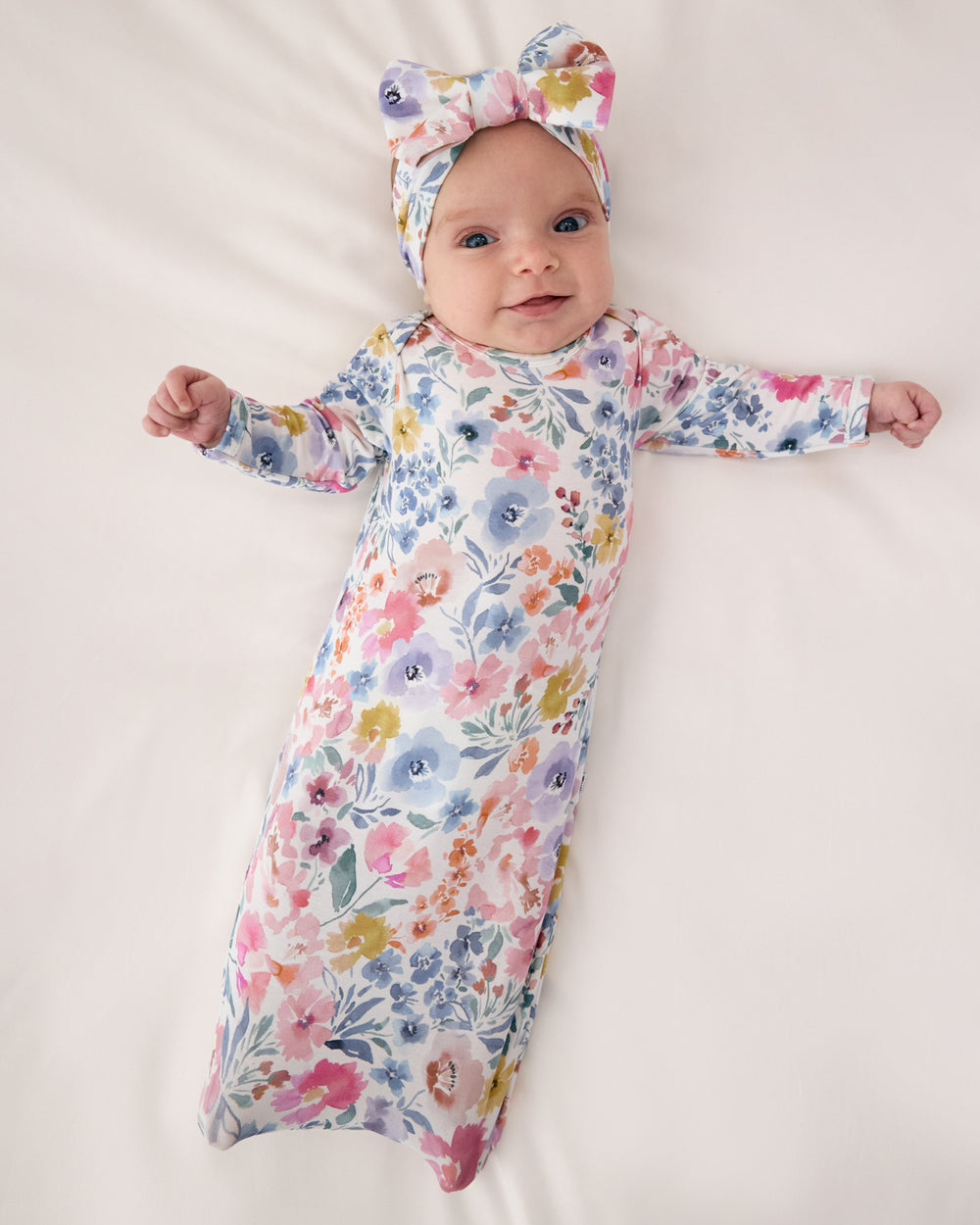 Aerial view of baby wearing the Tiny Blooms Infant Gown with a matching luxe bow headband 