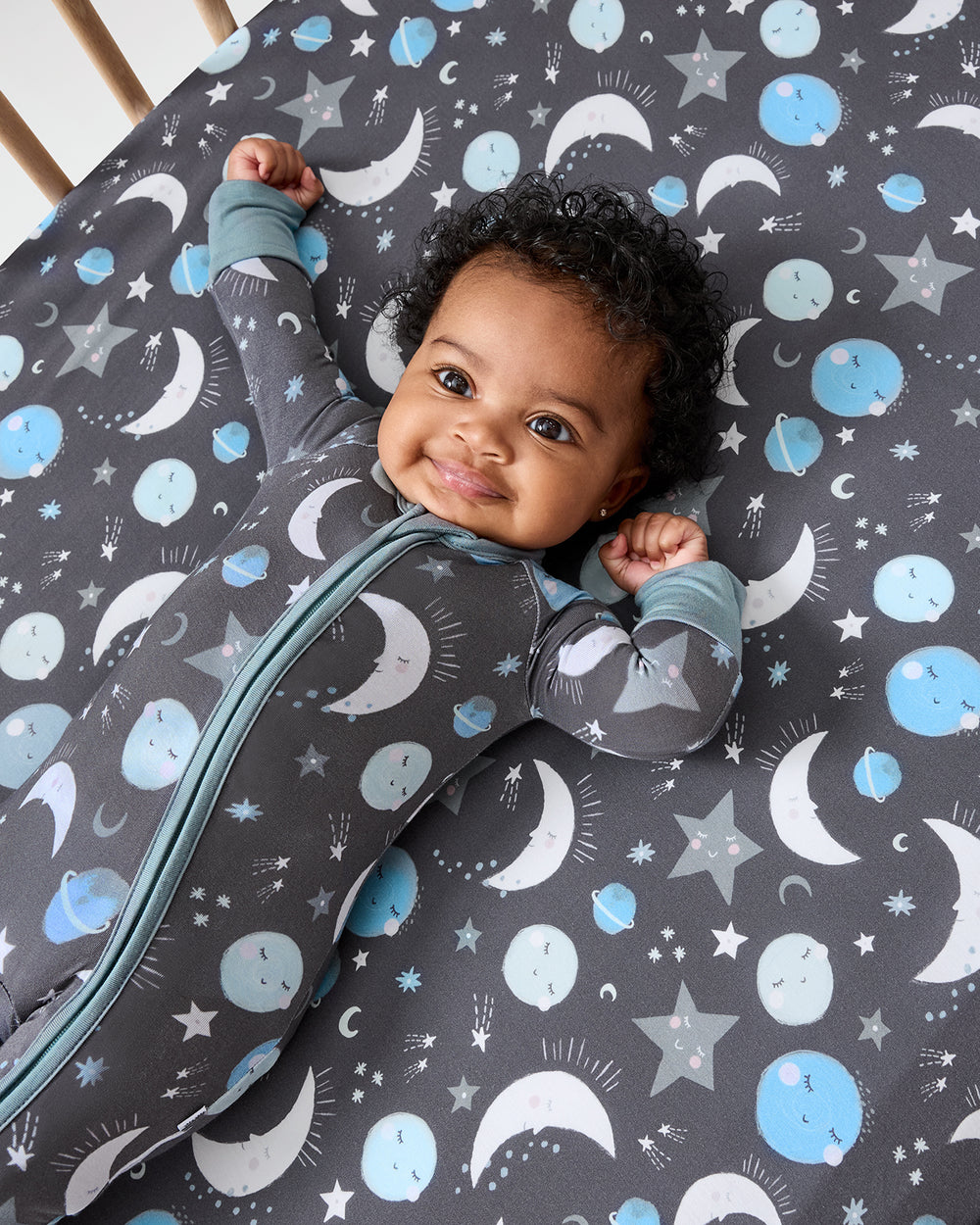 Baby laying on the Blue To the Moon & Back Fitted Crib Sheet