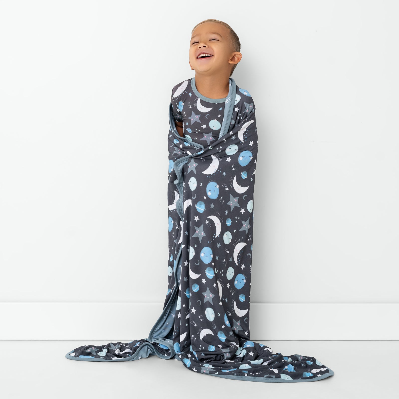 Standing child wrapped in the Blue To the Moon & Back Large Cloud Blanket®