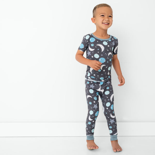 Standing child wearing the Blue To the Moon & Back Two-Piece Short Sleeve Pajama Set
