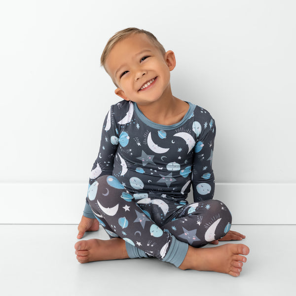 Sitting child wearing the Blue To the Moon & Back Two-Piece Pajama Set