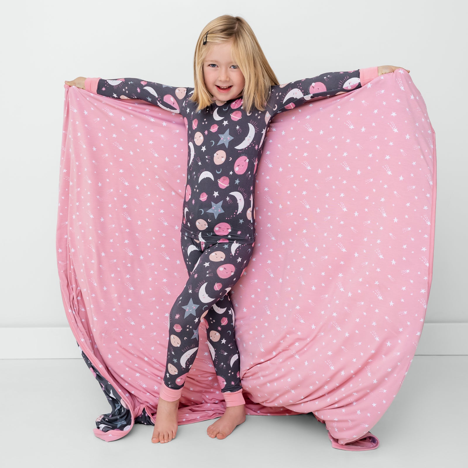 Posing child holding up the Pink To the Moon & Back Large Cloud Blanket®