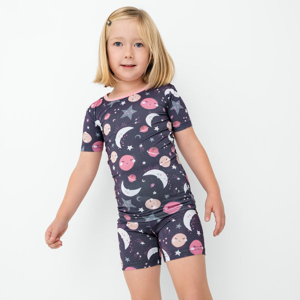 Standing child wearing the Pink To the Moon & Back Two-Piece Short Sleeve & Shorts Pajama Set