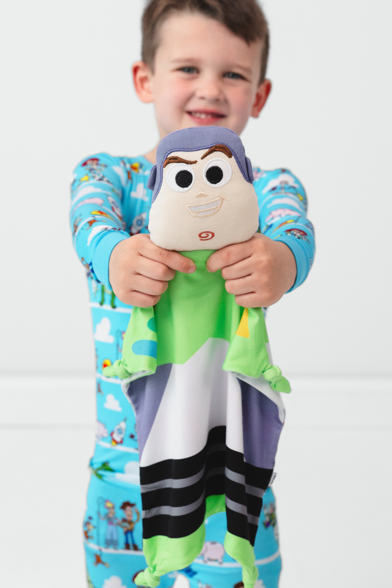 child wearing disney & pixar toy story pals two-piece pajama set and holding a pixar buzz lightyear lovey