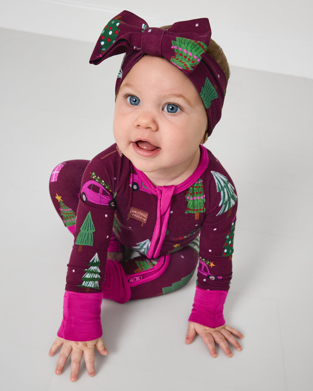 Crawling baby wearing the Cranberry Tree Traffic Luxe Bow Headband with a matching zipper pajama