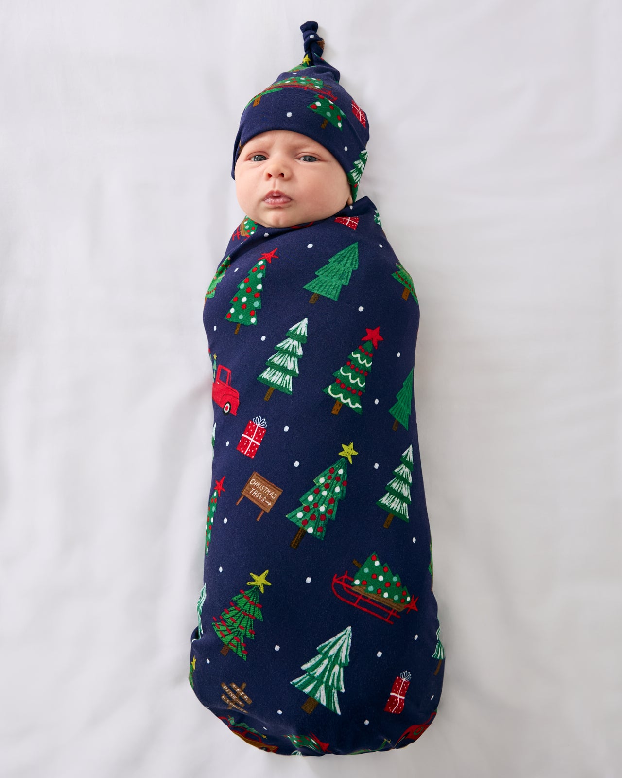 Aerial view of baby wearing the Navy Tree Traffic Swaddle & Hat Set
