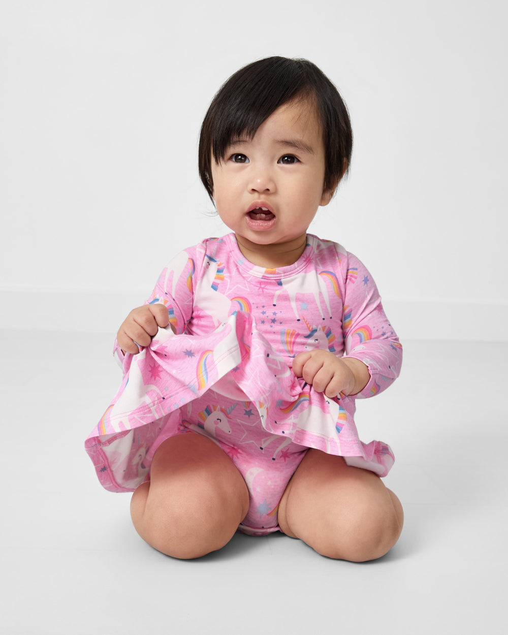 Sitting child wearing the Unicorn Dance Twirl Dress with Bodysuit