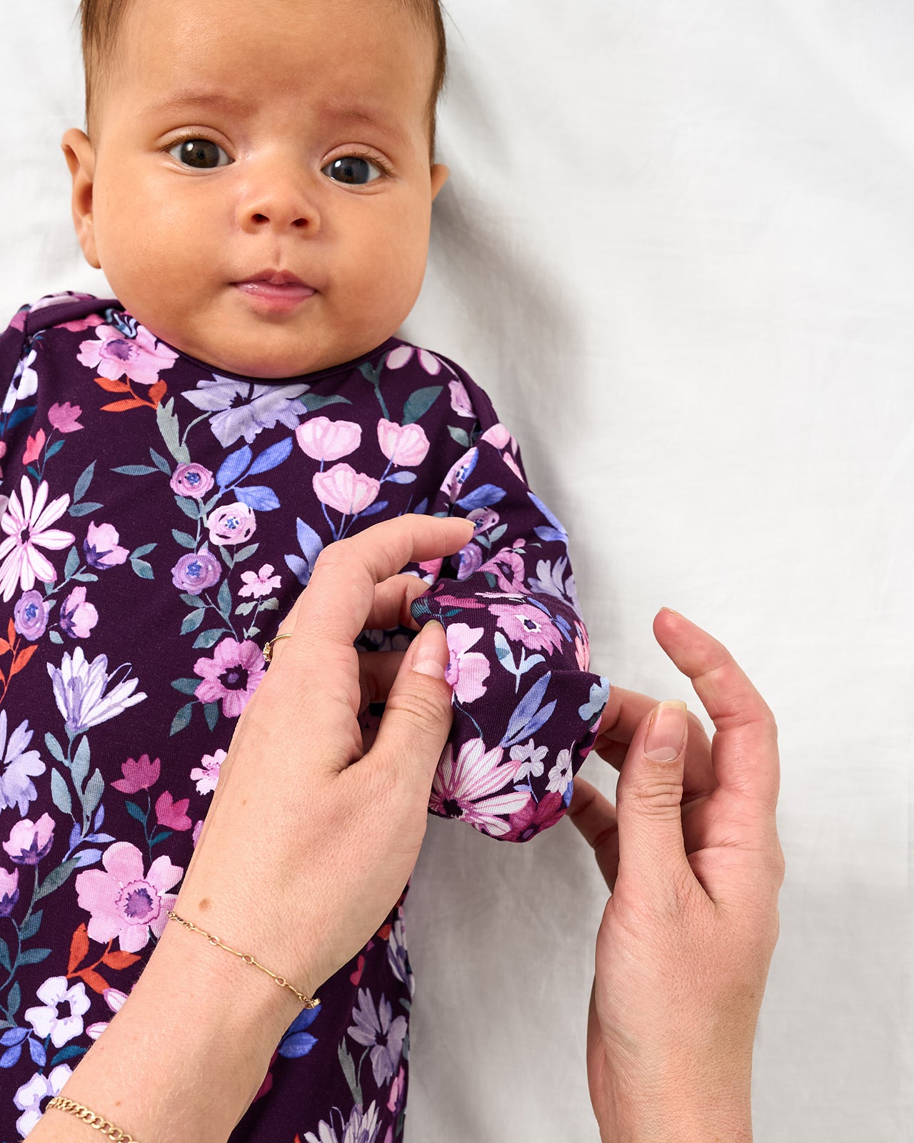 Adult demonstrating the mitten feature on the Violet Meadow Infant Gown