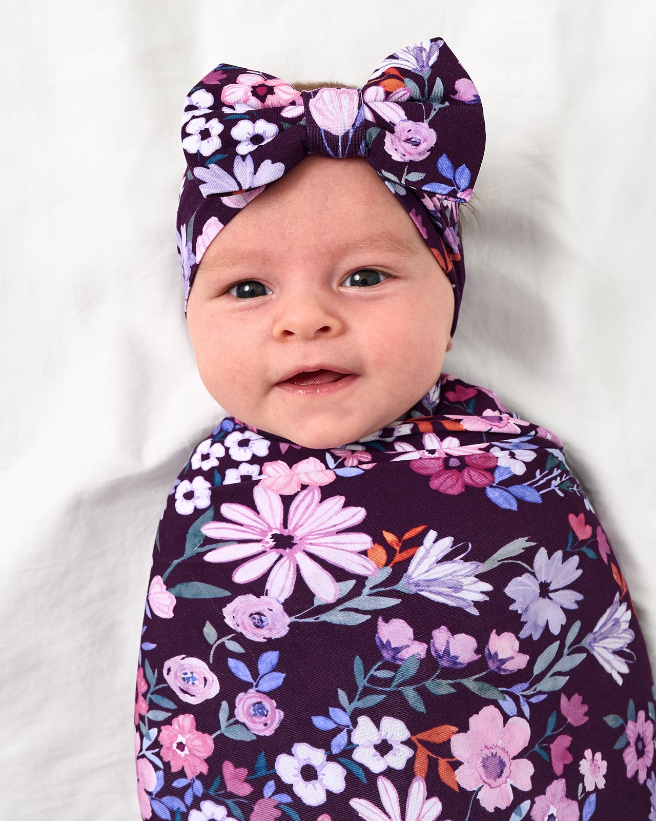 Close up of baby wearing the Violet Meadow Swaddle & Luxe Bow Headband Set