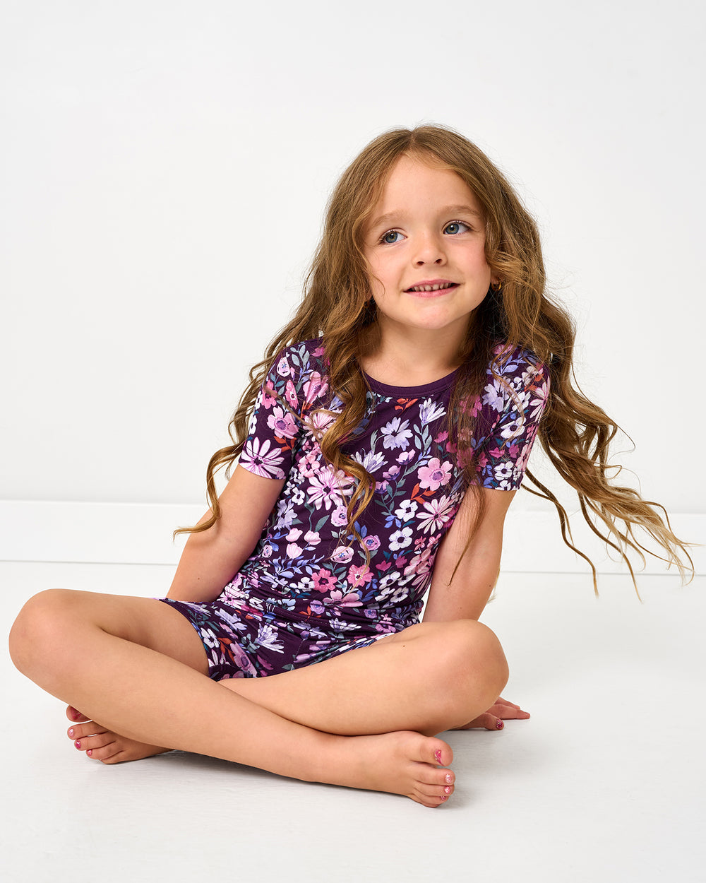 Sitting girl wearing the Violet Meadow Two-Piece Short Sleeve & Shorts Pajama Set