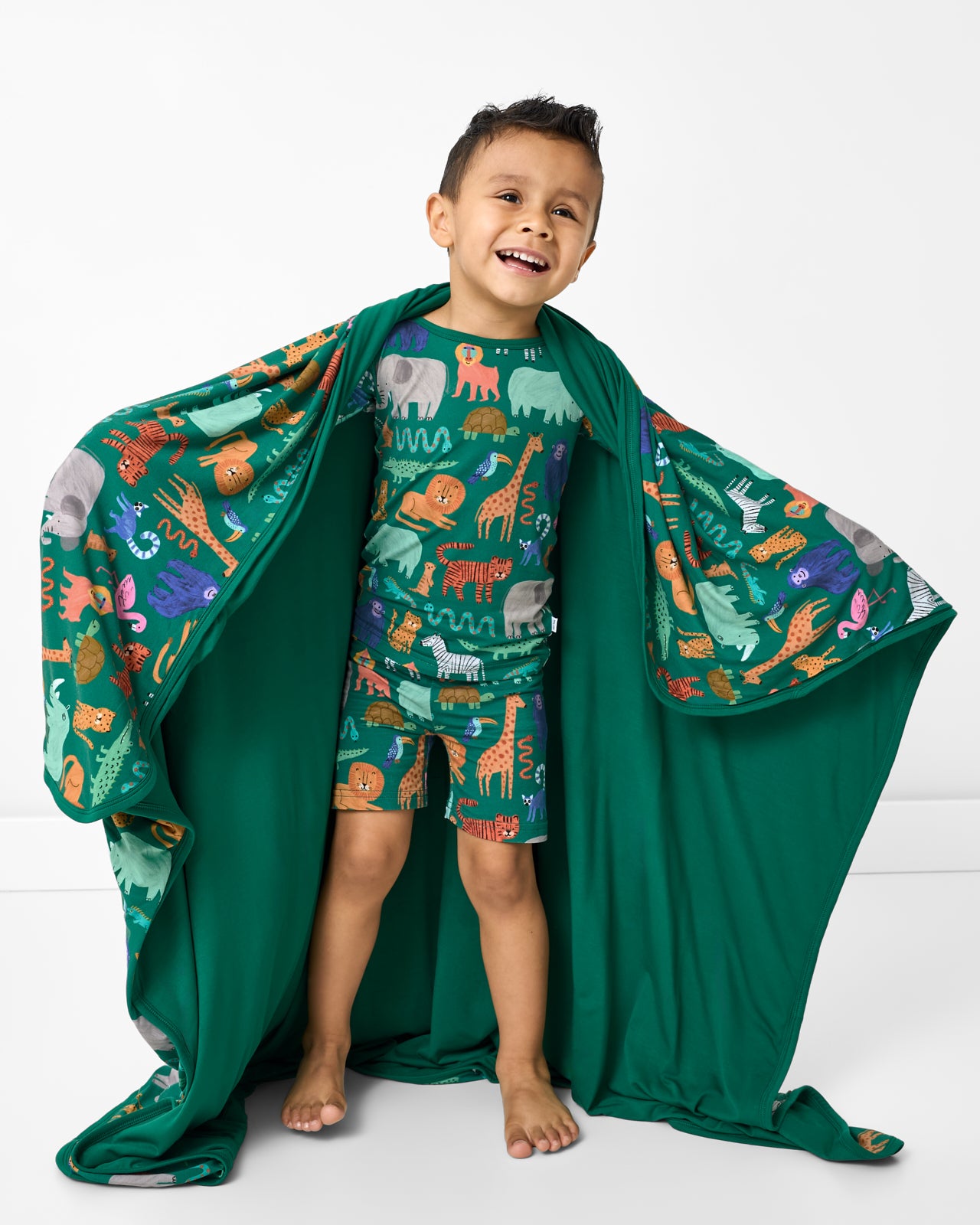 Boy wrapped in the Wild Zoo Large Cloud Blanket® showing the solid green side