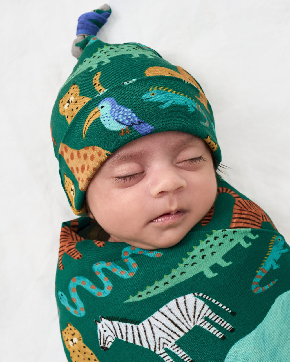 Close up of baby wearing the Wild Zoo Swaddle & Hat Set