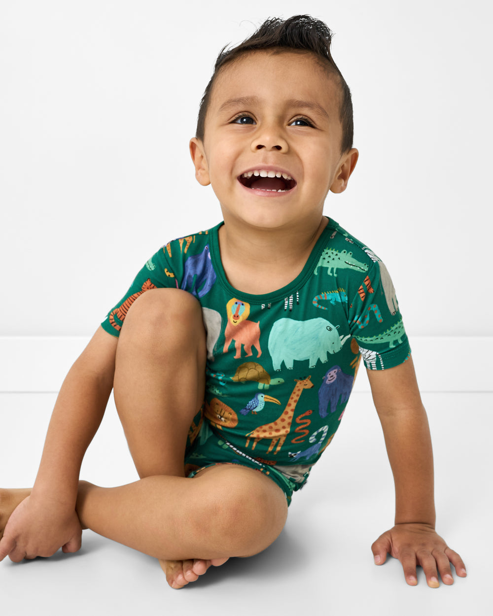 Sitting boy wearing the Wild Zoo Two-Piece Short Sleeve & Shorts Pajama Set