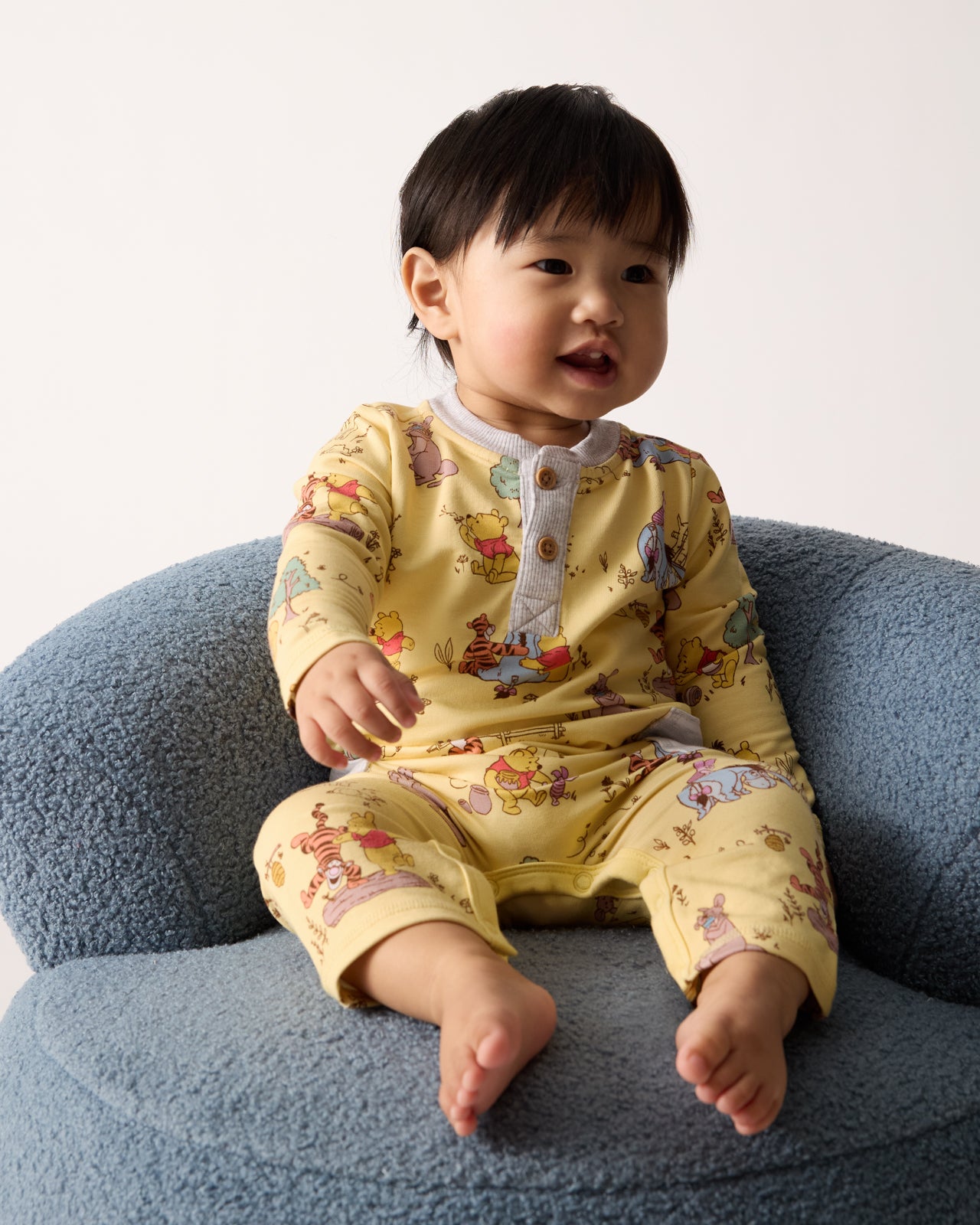 Baby sitting on a chair wearing the Disney Playtime With Pooh Henley Romper