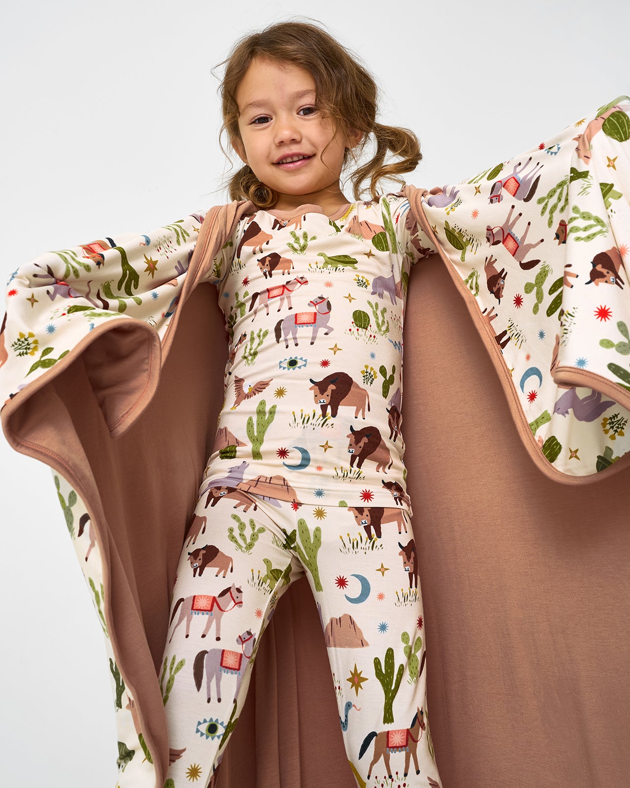 Girl wrapped in the Wild Frontier Large Cloud Blanket® wearing the matching pajama set