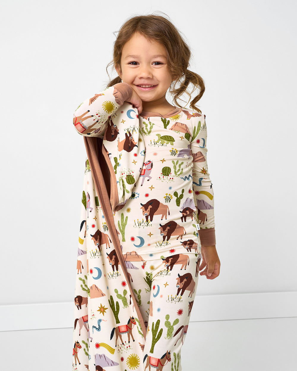 Girl wearing the Wild Frontier pj set holding the matching Large Cloud Blanket®