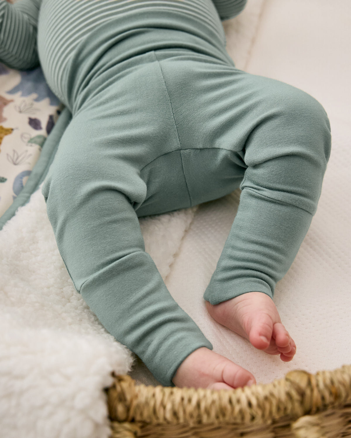Baby in a basket crib wearing the Willow Fold-over Newborn Leggings
