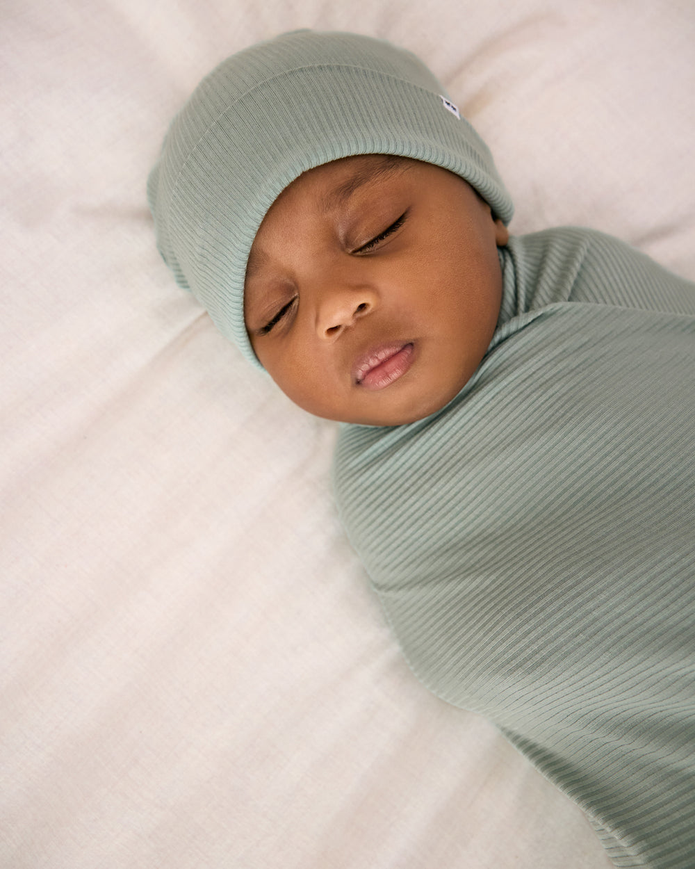 Alternate close up of newborn swaddled in the Willow Baby Ribbed Swaddle & Infant Beanie Set