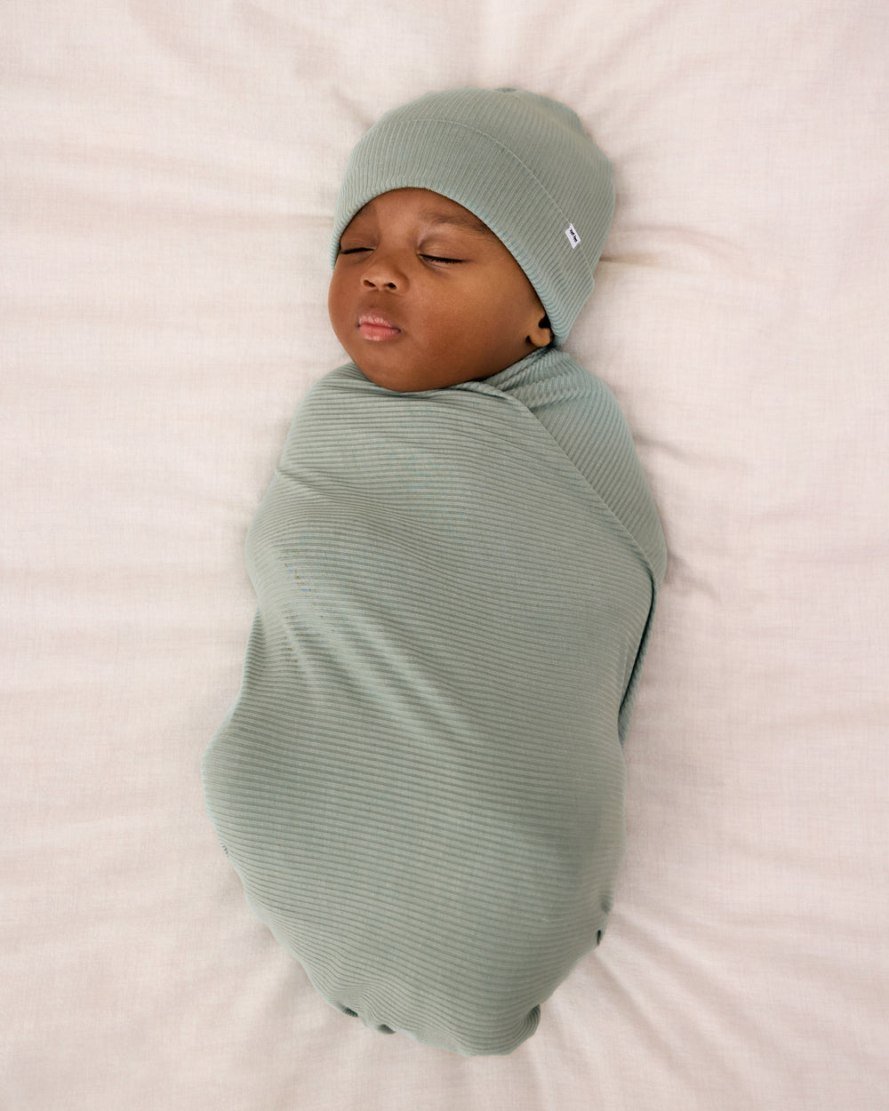 Aerial view of newborn swaddle in the Willow Baby Ribbed Swaddle & Infant Beanie Set