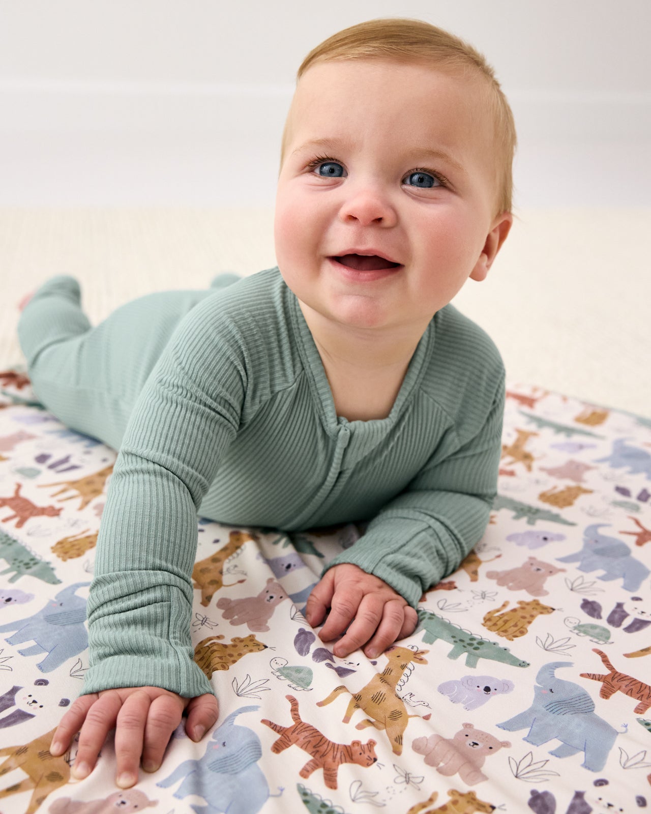 Newborn wearing the Willow Ribbed Zippy laying on a safari themed baby blanket