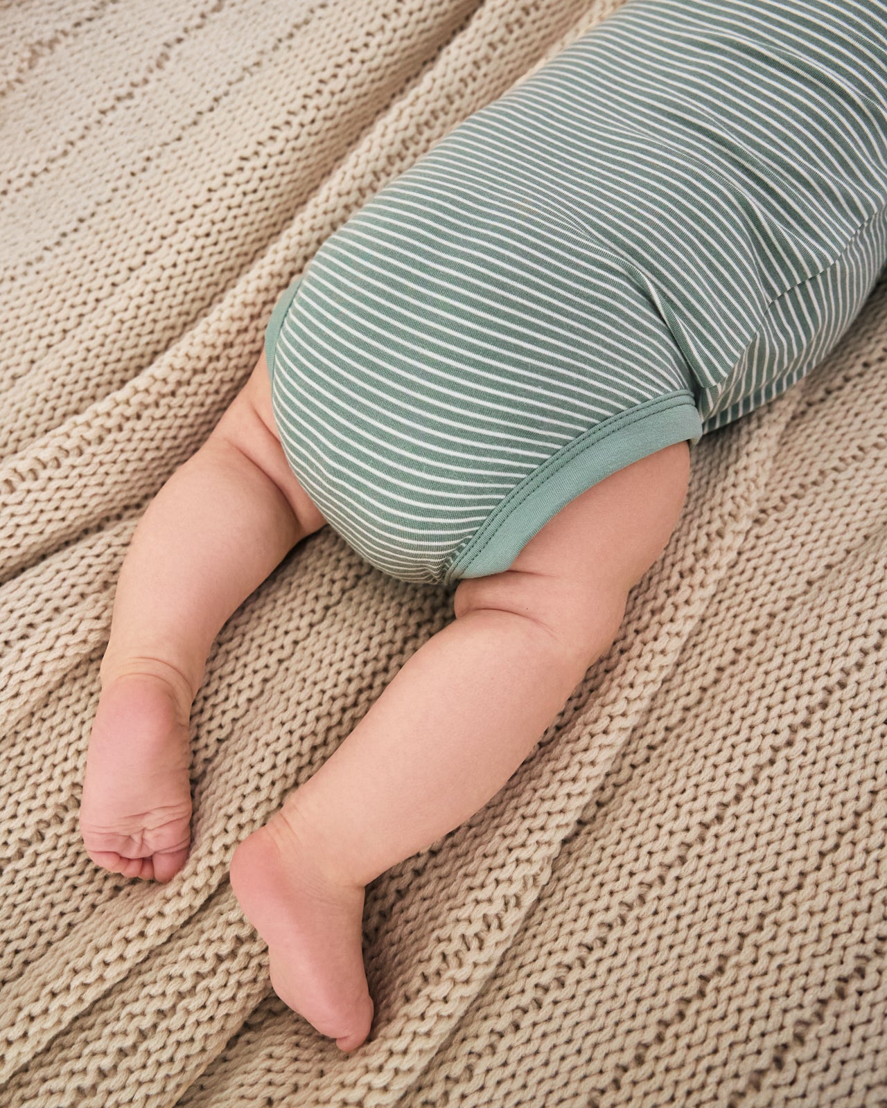 Newborn laying on a blanket wearing the Willow Stripe Henley Bodysuit