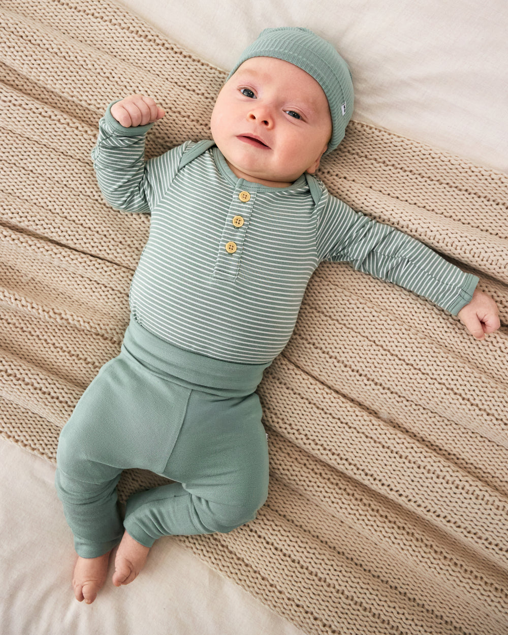 Aerial view of newborn wearing the Willow Stripe Henley Bodysuit with matching green leggings