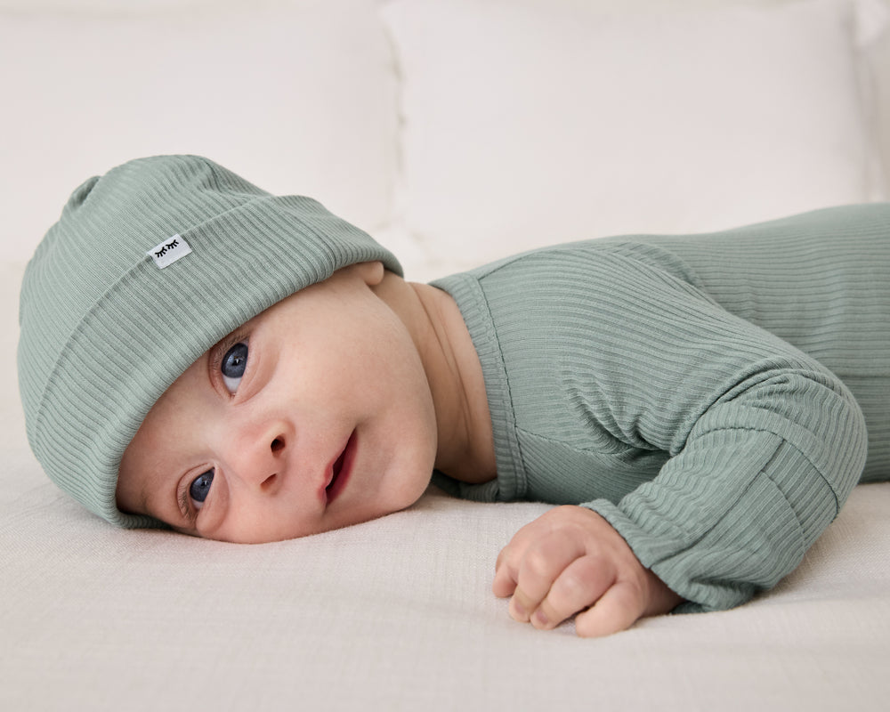 Newborn on his tummy wearing the Willow Ribbed Infant Beanie