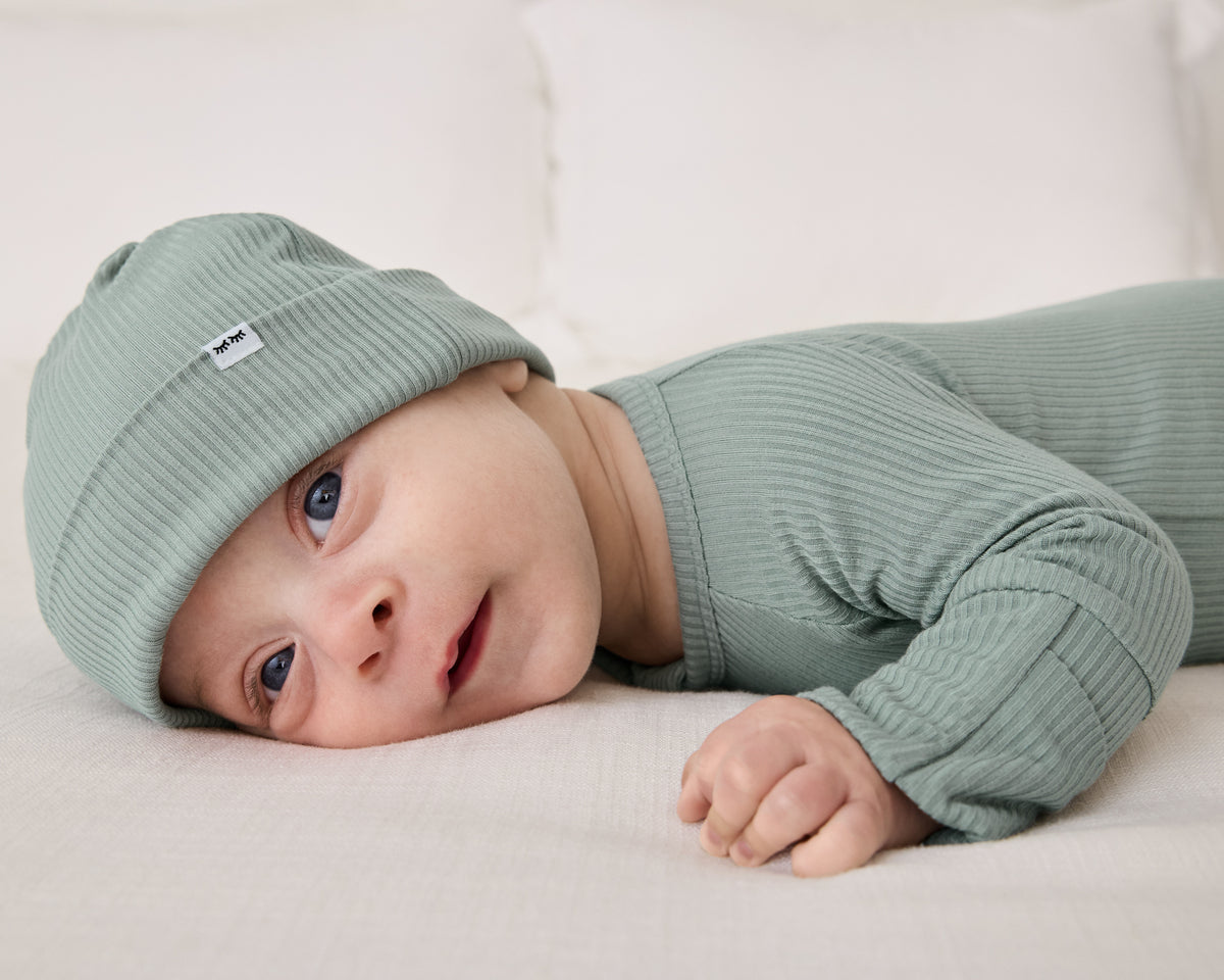 Newborn on his tummy wearing the Willow Ribbed Infant Beanie