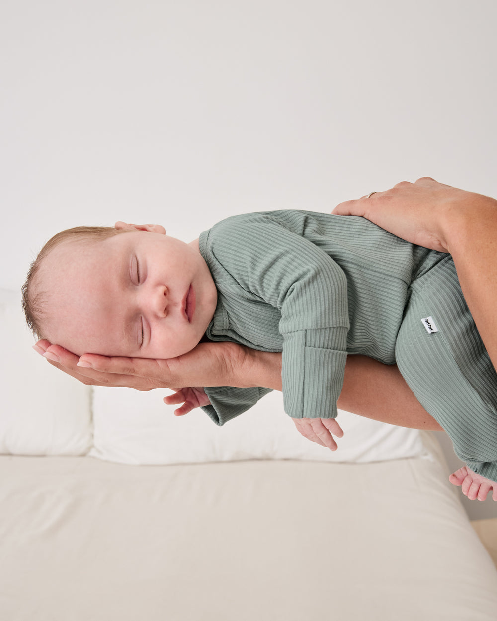 Adult holding sleeping newborn wearing the Willow Ribbed Zippy